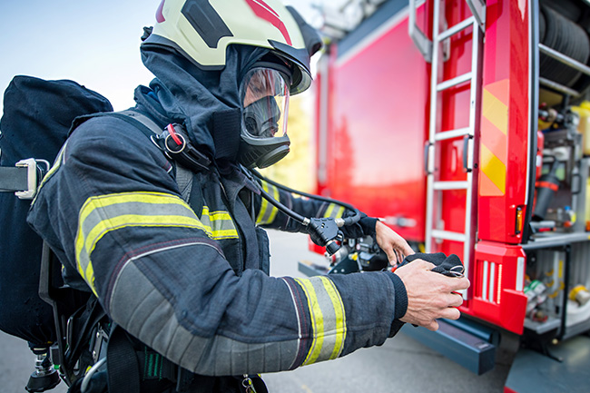 Feuerwehrmann der neben dem Feuerwehrauto steht.